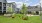 a grassy area with trees and buildings behind it